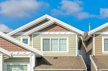 Top of grey stucco luxury house with shingle roof, red and yellow trees and nice windows in Summer in Vancouver, Canada, North America. Day time on June 2024.