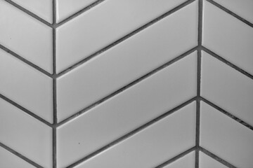 A close-up of a herringbone-patterned tile wall in shades of gray, showcasing a modern and elegant design.