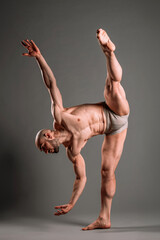 Strong beard man doing dance pose on barefoot near wall