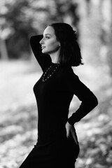 Portrait of a young beautiful dark-haired girl in the park. Black and white photo.