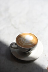 A perfectly crafted cappuccino with intricate latte art in a heart design, served in a white...