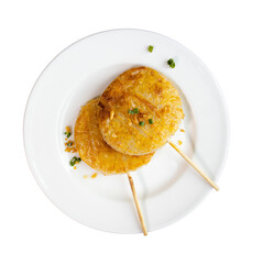 A plate with two golden, crispy cakes on sticks, garnished with green onions.
