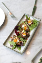 Crispy Lebanese kibbeh bites garnished with creamy yogurt, apricots, and pomegranate seeds, served over fresh greens for a vibrant and flavorful appetizer.
