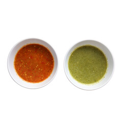 Two bowls of vibrant sauces, one red and one green, showcasing rich textures and colors.