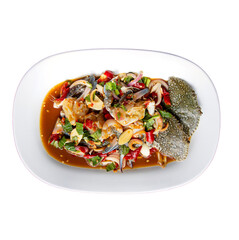 A vibrant dish featuring seafood, fresh vegetables, and a rich sauce, artfully arranged on a white plate.