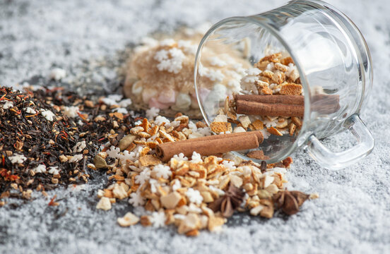winter hot drink ingredient spiled with spices, star-shaped and sugar and glass cup turn over on snowy background