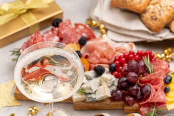 Glass of champagne, Prosecco or white  wine , festive aperitif or party food and drink with cold meat appetizers cheeses and olives , party food for New Year's Eve, Christmas or birthday