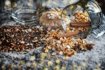 winter hot drink ingredient spilled with spices, star-shaped sugar and glass cup turn over on snowy background and golden blur lights