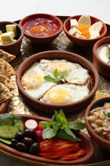 A traditional Lebanese breakfast spread featuring fried eggs, zaatar, hummus, labneh, butter, apricot jam, fresh vegetables, olives, and Lebanese bread, beautifully arranged on a rustic tray.
