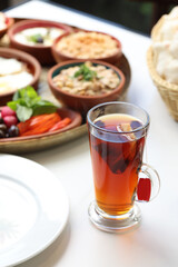 A traditional Lebanese breakfast spread featuring fried eggs, zaatar, hummus, labneh, butter, apricot jam, fresh vegetables, olives, Lebanese bread, and a warm cup of tea, beautifully arranged on a ru