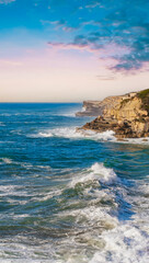 Coast and sea, beautiful rocky shore. Sunset over stoned coast and ocean fresh water splashing against rocky coast. Restless blue sea