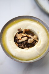  A close-up view of a creamy hummus bowl topped with roasted almonds, ground beef, and a drizzle of olive oil, showcasing authentic Middle Eastern culinary tradition.