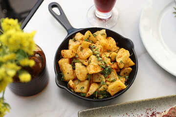A skillet of crispy batata harra (spicy Lebanese potatoes) sautéed with garlic and garnished with...
