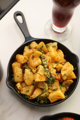 A skillet of crispy batata harra (spicy Lebanese potatoes) sautéed with garlic and garnished with fresh parsley, offering a flavorful and authentic Middle Eastern side dish.