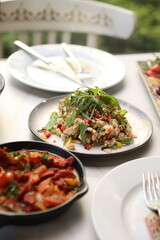 A skillet of Lebanese makanek sausages cooked with sautéed onions, tomatoes, and garlic in a rich, tangy tomato-based sauce, garnished with fresh parsley.