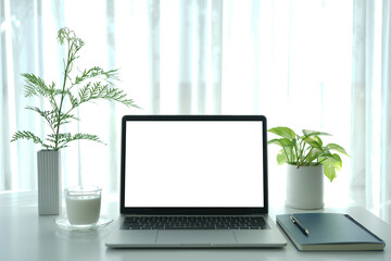 Laptop and notebook and milk on white table, interior workspace