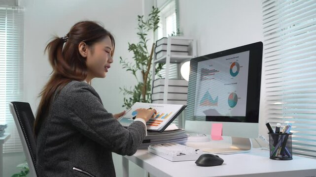 Businesswoman working with charts on a computer shows increasing stress and frustration in a corporate office setting