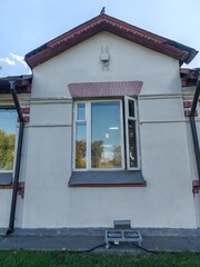 A traditional building with red accents and a tall, sloped roof, framed by trees on a sunny day. The architecture reflects the elegance of classical design, rooted in cultural history and preservation