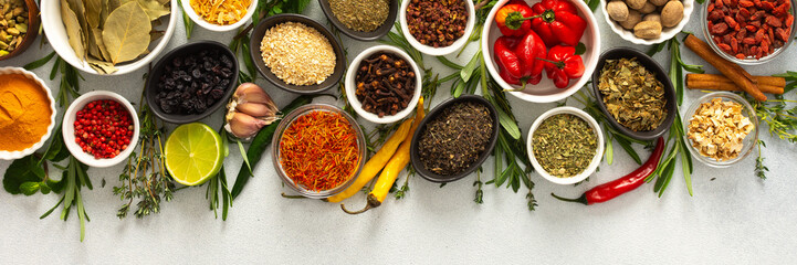Assorted cooking spices and herbs arranged on a gray surface, featuring natural tones that add depth and aroma to any meal, banner