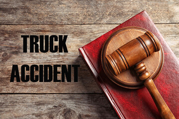 Truck accident law. Judge's gavel and book on wooden table, top view
