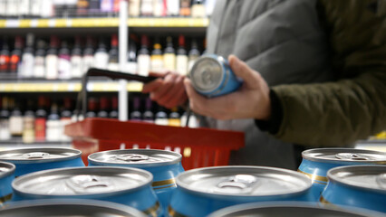 A male buyer places a beer can into a shopping cart