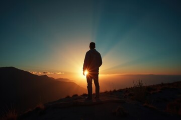 Fototapeta premium Silhouette of a man watching a sunset over mountains