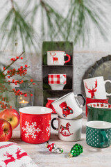 Kolekcja świątecznych kolorowych kubków na rustykalnym tle. © Dorota