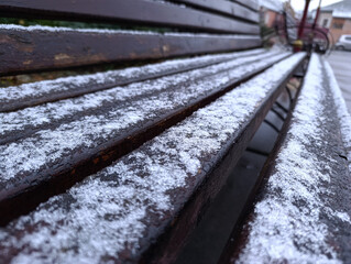 A wooden bench covered in snow on a sidewalk