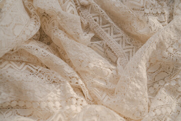 Abstract neutral background, crumpled draped elegant folds of openwork lace cloth, sun light with soft shadows, aesthetic sustainable bohemian backdrop, copy space