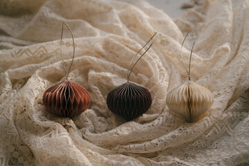 Christmas, New Year composition. Aesthetic Scandinavian Christmas paper honeycomb ornaments on crumpled draped elegant folds openwork lace cloth. Modern minimalist Christmas decoration. 