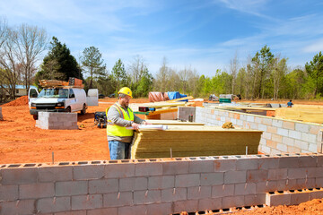 Construction worker in yellow hard hat vest organizes building materials at an active construction supervisor safety vest, hard hat studies blueprints