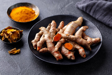 Fresh turmeric, curcuma, tumeric roots, powder and dried slices. Dark background. Close up.