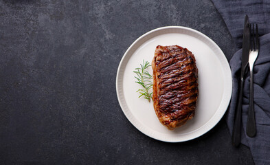 Beef Steak medium rare on a white plate. Dark background. Top view. Copy space.