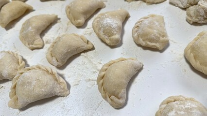 Traditional Ukrainian dish,Homemade Raw Dumplings on Floured Surface Ready for Cooking.A collection of uncooked homemade dumplings arranged on floured surface,highlighting fresh and rustic preparation
