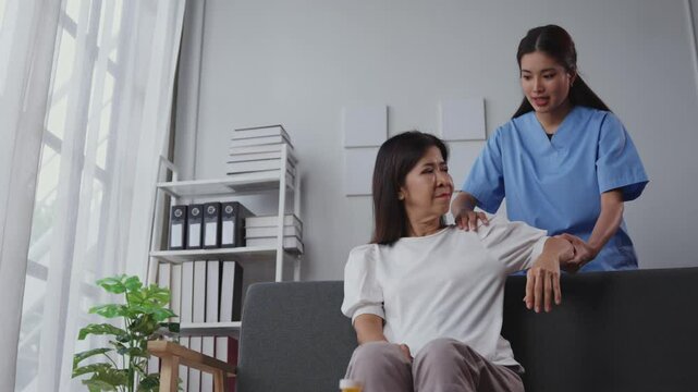 Nurse assisting a senior woman with arm exercises during a home visit, promoting recovery and mobility in a comfortable setting