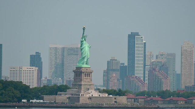 New York, USA, August 16, 2024. Fascinating vertical footage with a view of the Statue of Liberty as we pass by it by boat. Tourists can be seen on the island to visit it.