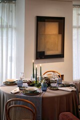 sophisticated table setting for dinner in a living room with candles in the center of the table