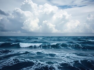 Fototapeta premium A seascape with towering clouds and ocean waves that seem to be swirling in a hypnotic dance, blue ocean, gentle lapping of the waves, driftwood