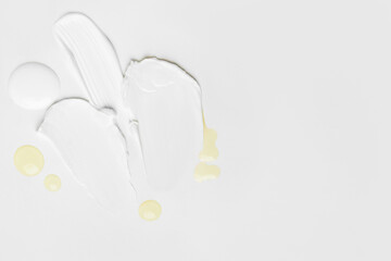 Beauty and skincare textures: cream smears, blue gel, transparent gel, and yellow drops on a light background featuring empty space