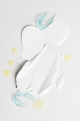 A beauty composition of cream, gel smudges, and drops in yellow, blue, and transparent tones on a light background
