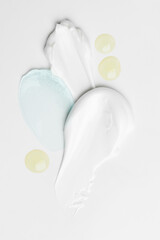 A variety of cosmetic product textures with cream, gel, and drops displayed on a light surface