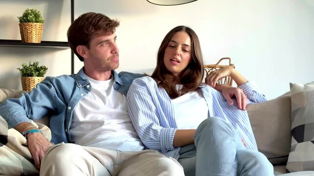 Partners sitting together on the sofa, smiling as they chat about their upcoming social plans, making future vacation arrangements, and discussing how they will spend their time off together