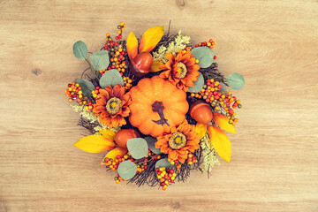 Autumn wreath of yellow leaves of  pumpkins and chestnuts  on wooden background