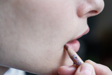 Beautiful woman paints her lips with cosmetic pencil. concept of care and beauty. Side view close-up.
