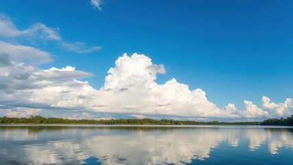 Fototapeta premium Softly lit clouds against a brilliant blue sky reflect beautifully on the calm surface of Apopka Lake in Winter Garden, creating a tranquil atmosphere, winter garden, tranquility