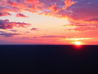 Fototapeta premium Vibrant oranges and purples dance across a canvas of deep blues as the sun dips below the horizon, deep blue tones, natural wonder