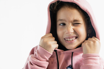 Playful girl winking and pulling hoodie strings in studio, copy space. © Raquel