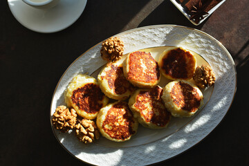 Vanilla nut cottage cheese pancakes ( syrniki or curd fritters) decorated with walnuts on white plate in sunny morning. High-protein breakfast ideas.