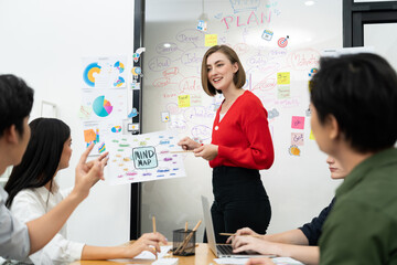 Professional young leader present business idea by using mind map at business meeting surrounded by professional cooperate colleague discussing and brainstorming about her strategy. Immaculate.