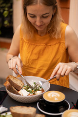 Woman eating tasty Shakshuka at cafe. Middle eastern traditional dish. Fried eggs with tomatoes and cup of coffee. Concept of easy breakfast. Food banner